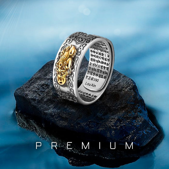 Anel prateado com símbolo dourado de Pixiu e gravações internas de mantra, estilo Feng Shui, Pelicano Azul.