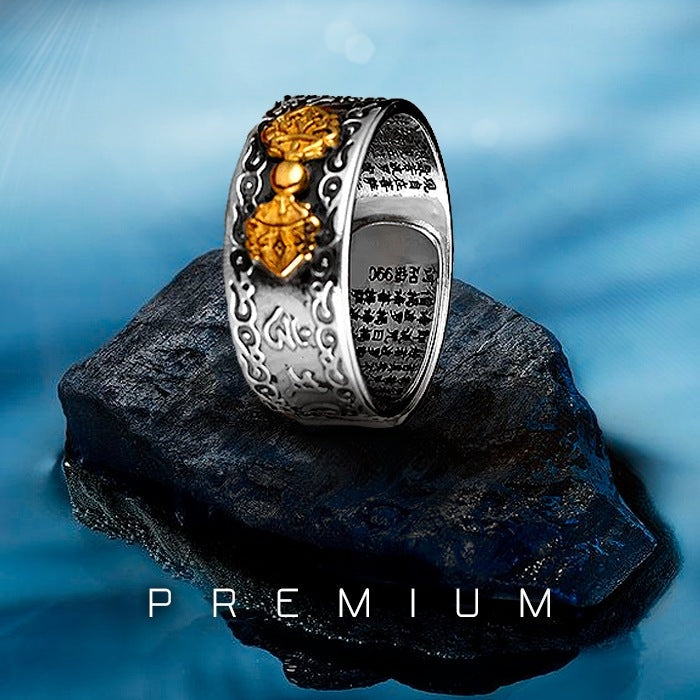 Anel Feng Shui em prata 990 com símbolos Vajra dourados em destaque, sobre uma pedra com fundo azul, Pelicano Azul.