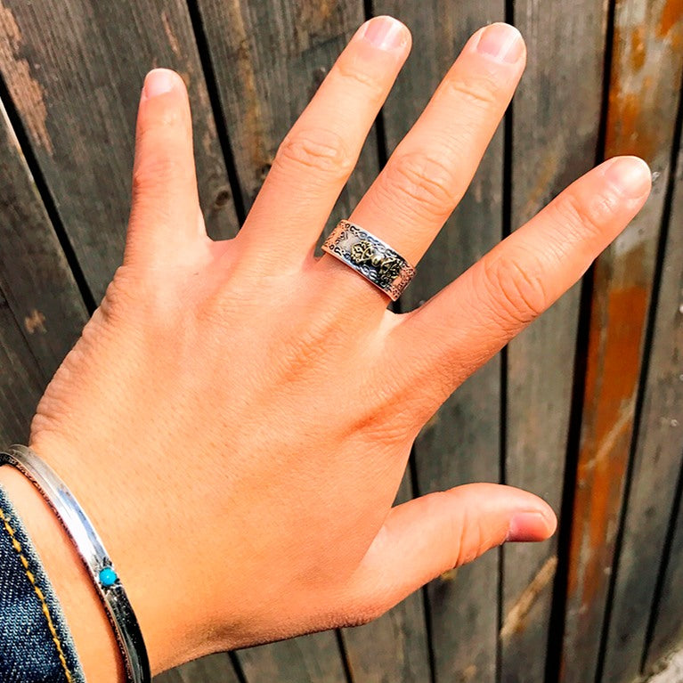 Anel Feng Shui Vajra em prata 990 no dedo, com detalhes simbólicos dourados e prata, Pelicano Azul.