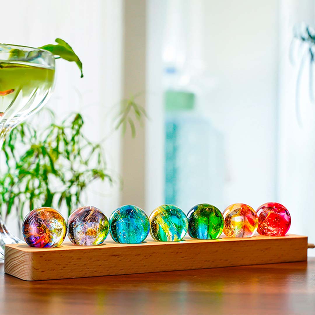 Luminária Pelicano Azul com sete esferas coloridas sobre base de madeira, criando um ambiente harmonioso e acolhedor.