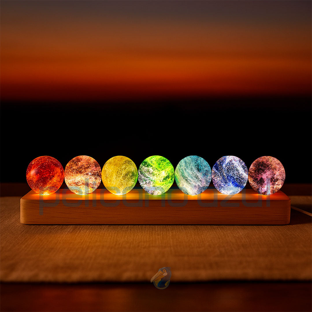 Luminária com esferas coloridas dos 7 chakras sobre base de madeira em ambiente escuro.