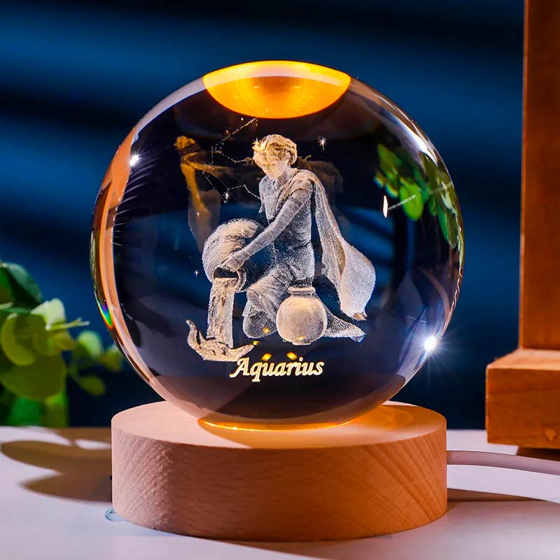 Luminária de cristal com o signo de aquario gravado em 3D, iluminada por LED, criando um efeito celestial. Ideal para representar o equilíbrio e a harmonia do signo de aquário. Pelicano Azul.