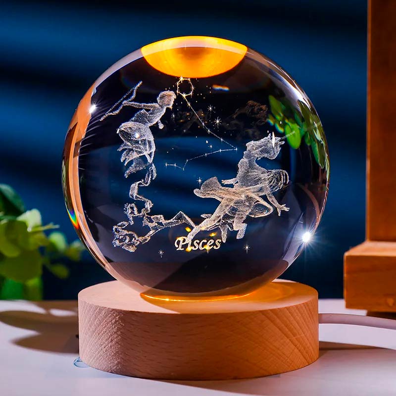 Luminária de cristal com o signo de peixes gravado em 3D, iluminada por LED, criando um efeito celestial. Ideal para representar o equilíbrio e a harmonia do signo de peixes. Pelicano Azul.
