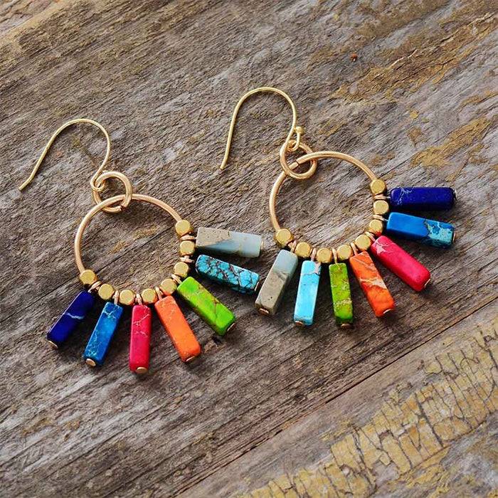 Brincos com pedras coloridas dos chakras, promovendo equilíbrio e estilo com um design espiritual e moderno Pelicano Azul.