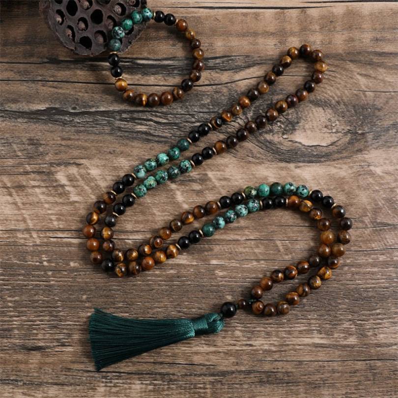 Japamala com 108 contas em Ônix Negro, Olho de Tigre e Turquesa Africana, com um elegante tassel verde. Acompanha pulseira combinando Pelicano Azul