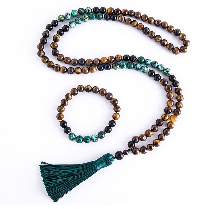 Japamala com 108 contas em Ônix Negro, Olho de Tigre e Turquesa Africana, com um elegante tassel verde. Acompanha pulseira combinando Pelicano Azul