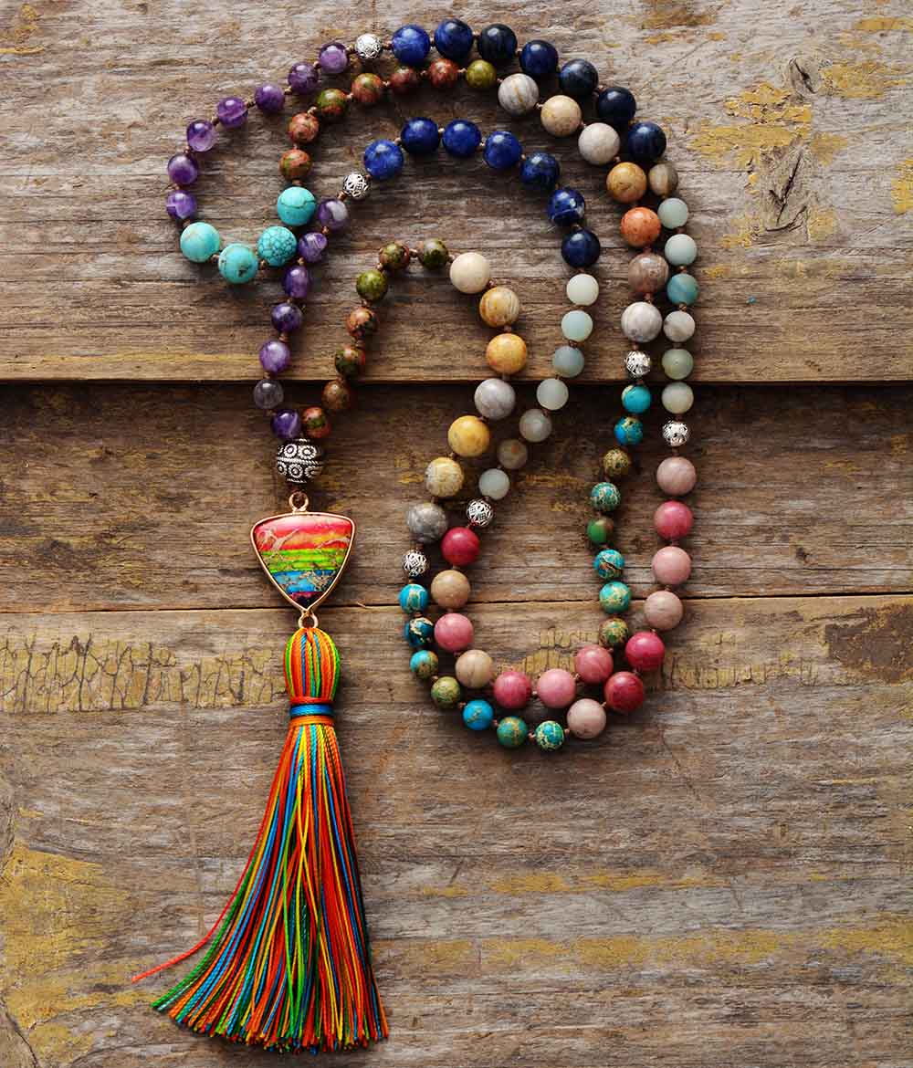 Japamala da Ativação dos 7 Chakras com pedras naturais em tons vibrantes e pingente multicolorido, finalizado com um tassel azul e verde Pelicano Azul.