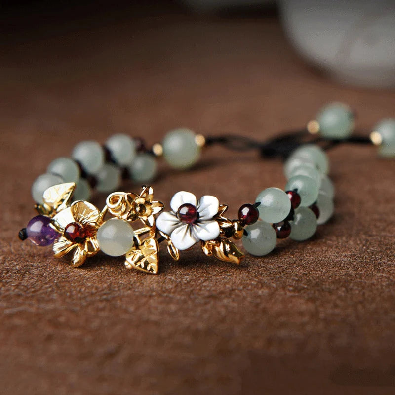 Pulseira Flores de Jade em tom verde suave, com detalhes florais em metal dourado e branco, trazendo elegância e um toque natural - Pelicano Azul.