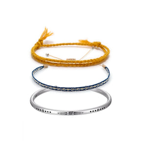 Conjunto budista com duas pulseiras, corda amarela e fio azul, e bracelete de prata tibetana gravado, simbolizando fé e proteção espiritual - Pelicano Azul