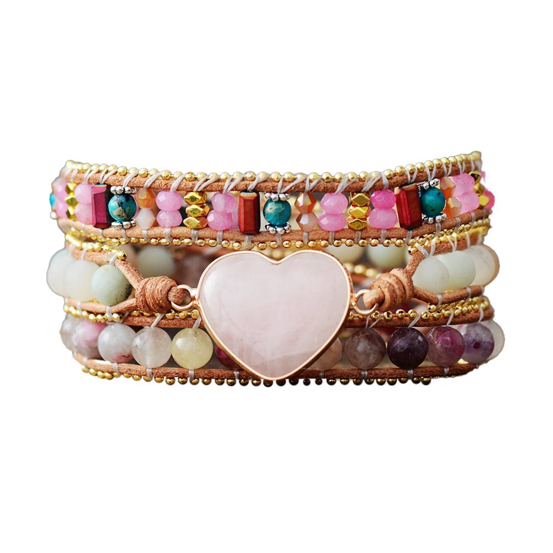 Pulseira com várias camadas de contas multicoloridas, incluindo cristais, pedras naturais e elementos metálicos, com um grande coração central de quartzo rosa, Pelicano Azul.