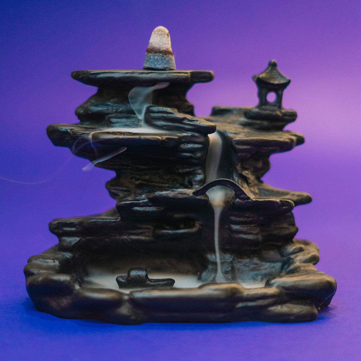  Incensário Cachoeira de Rozan em cerâmica preta, com fluxo reverso da fumaça criando efeito de queda d'água, proporcionando serenidade Pelicano Azul.