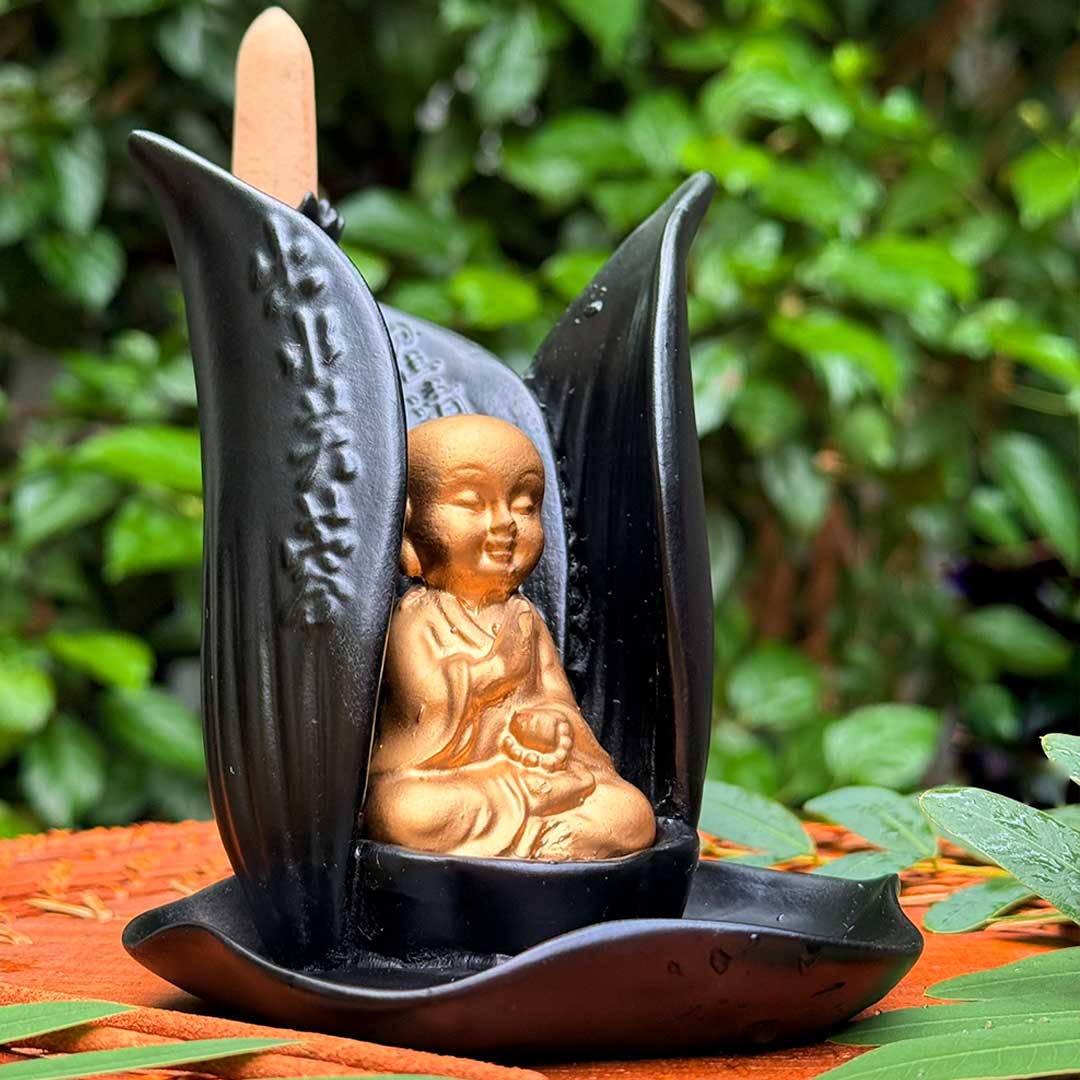 Incensário Lótus de Buda Pelicano Azul, em cerâmica preta, com inscrições orientais e Buda dourado meditando.