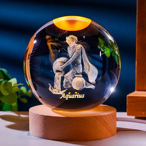 Luminária de cristal com o signo de aquario gravado em 3D, iluminada por LED, criando um efeito celestial. Ideal para representar o equilíbrio e a harmonia do signo de aquário. Pelicano Azul.