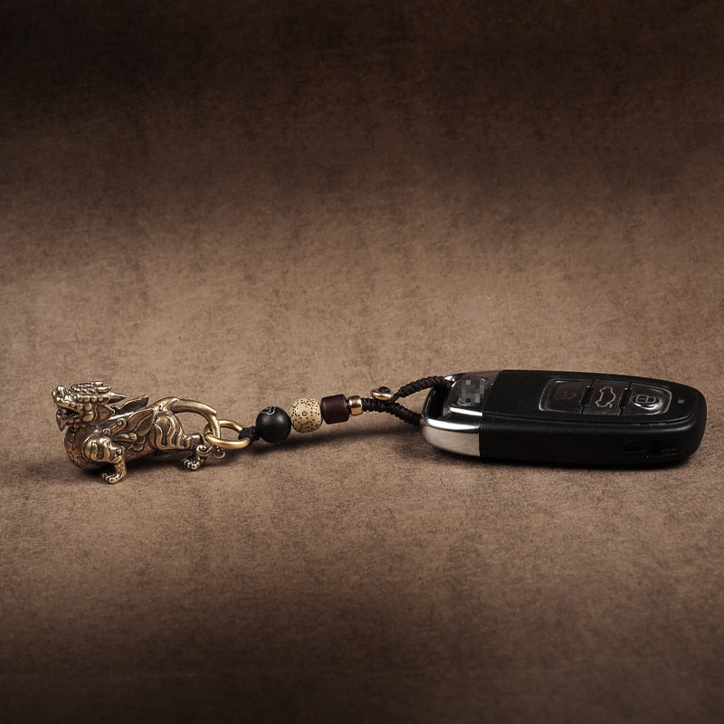 Chaveiro da sorte com Pixiu protetor em bronze, acompanhado de chaves, símbolo de proteção e prosperidade, Pelicano Azul.