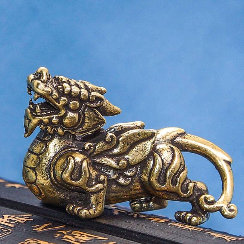 Estátua de Pixiu dourado em metal detalhado, símbolo de proteção e sorte, Pelicano Azul.