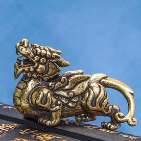 Estátua de Pixiu dourado em metal detalhado, símbolo de proteção e sorte, Pelicano Azul.