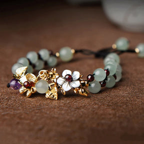 Pulseira Flores de Jade em tom verde suave, com detalhes florais em metal dourado e branco, trazendo elegância e um toque natural - Pelicano Azul.